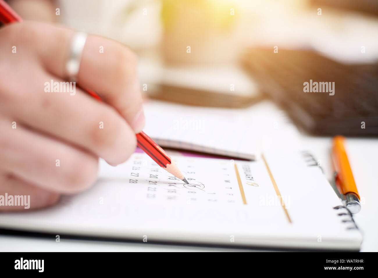Picture of Man writing on notebook with pen and holding mobile in hand ...