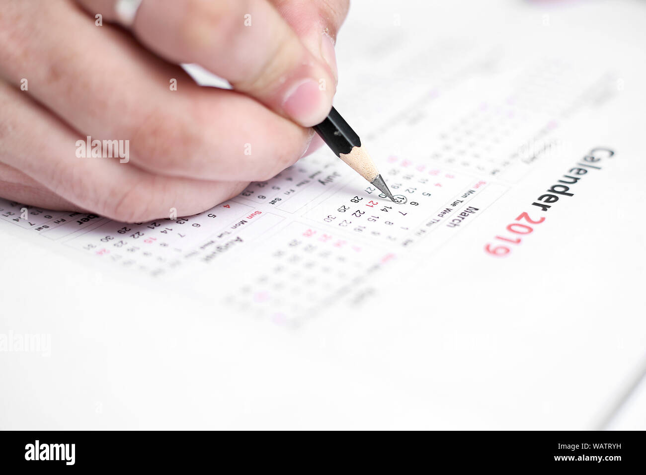 Picture of Man writing on a notebook with pen and holding mobile in ...