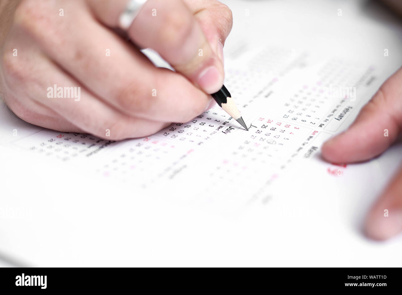 Picture of Man writing on a notebook with pen and holding mobile in ...