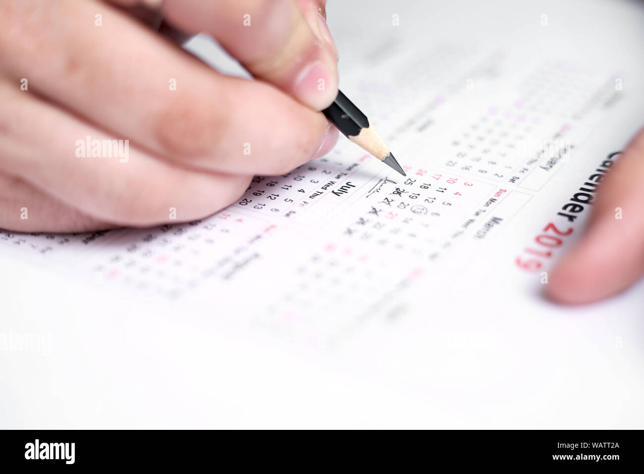 Picture of Man writing on a notebook with pen and holding mobile in ...