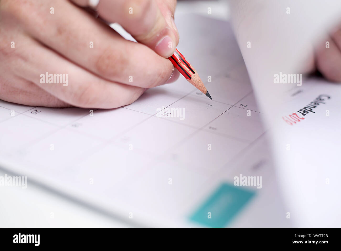 Picture of Man writing on a notebook with a pen and holding mobile in ...
