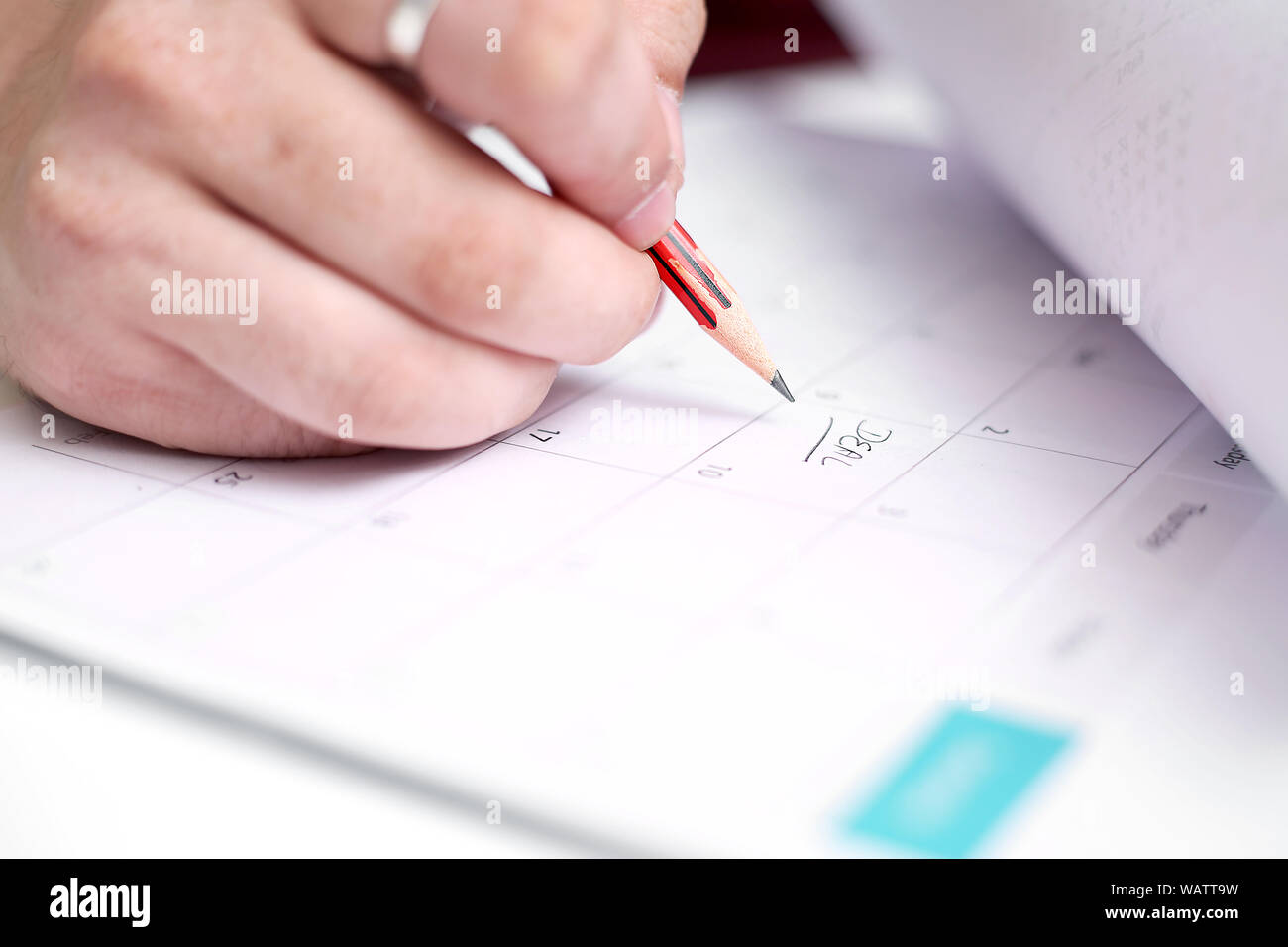 Picture of Man writing on notebook with pen and holding mobile in hand ...