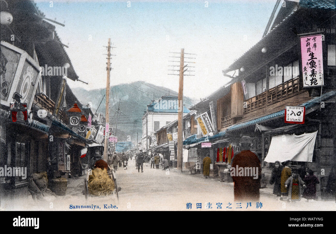 [ 1910s Japan - Shrine Street in Sannomiya, Kobe ] —   This postcard of Sannomiya in Kobe, Hyogo Prefecture shows Ikuta-mae, the street leading to the shinto shrine Ikuta Jinja.   In the background the shrine’s torii can be seen. One Western style building made of stone stands out among the otherwise traditional wooden architecture.   When Kobe opened its port for trade in 1868 (Meiji 1), this was a beautiful sand-road that lead from the shrine to the sea and was lined on both sides with plum and cherry trees and countless stone lanterns.  20th century vintage postcard. Stock Photo