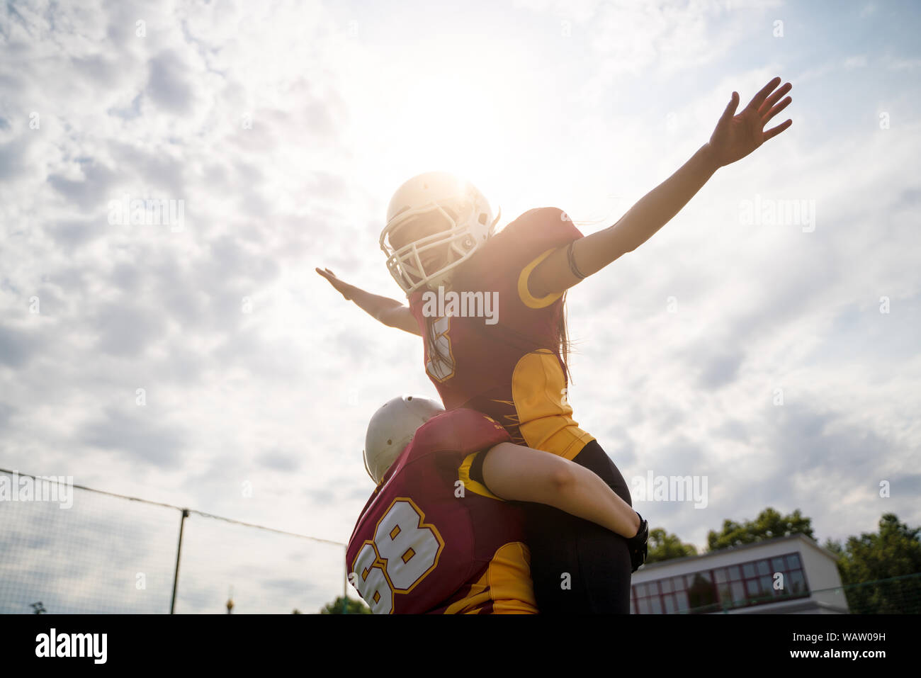 Photo of two American football woman athletes wearing helmets with their hands to side against cloudy sky on summer day Stock Photo