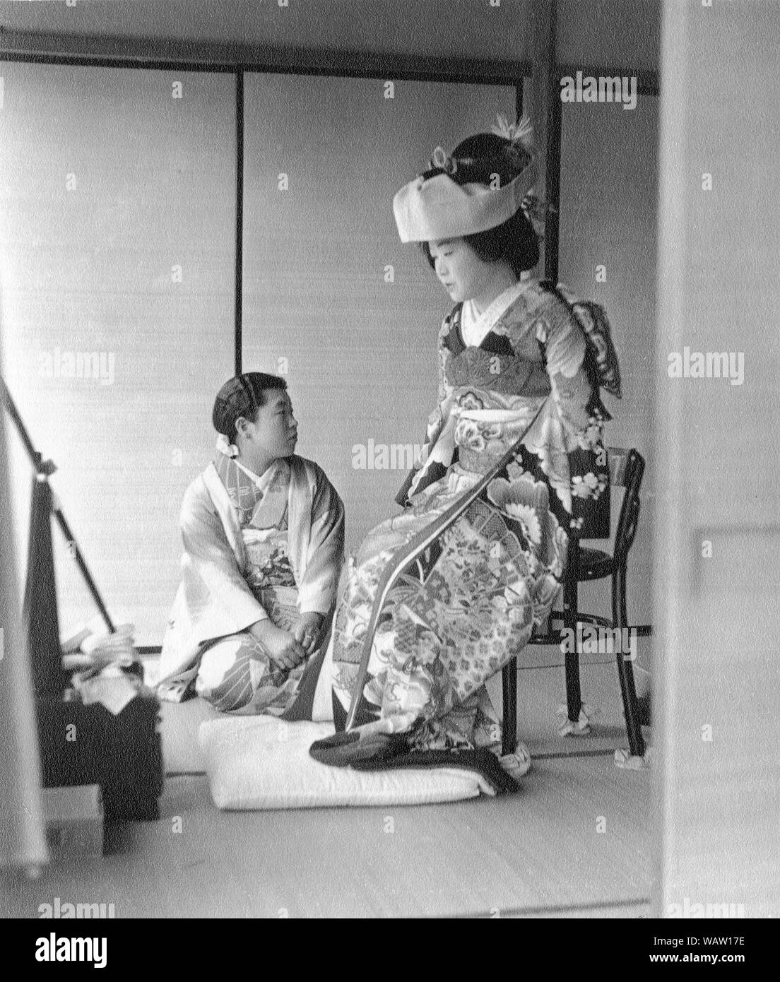 [ 1930s Japan - Japanese Bride in Wedding Kimono ] —   Bride just before the wedding.   A very intimate moment showing the bride wearing a traditional wedding kimono and tsunokakushi, headwear that 'hides' the bride's horns of jealousy, ego and selfishness. Tsunokakushi symbolizes the bride's resolve to become a gentle and obedient wife.   20th century vintage gelatin silver print. Stock Photo