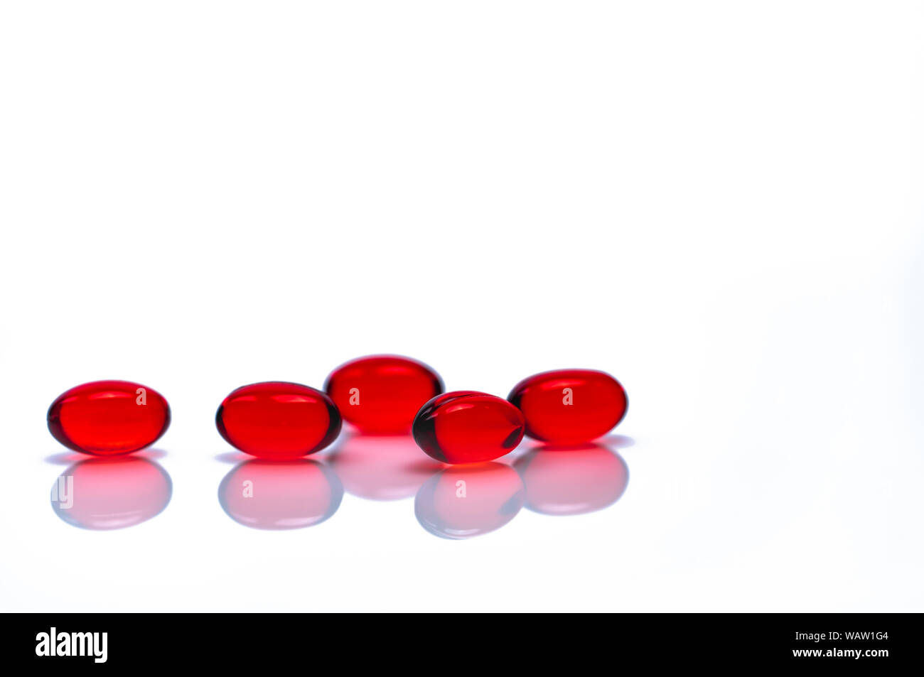 Red soft gel capsule pills isolated on white background. Pile of red