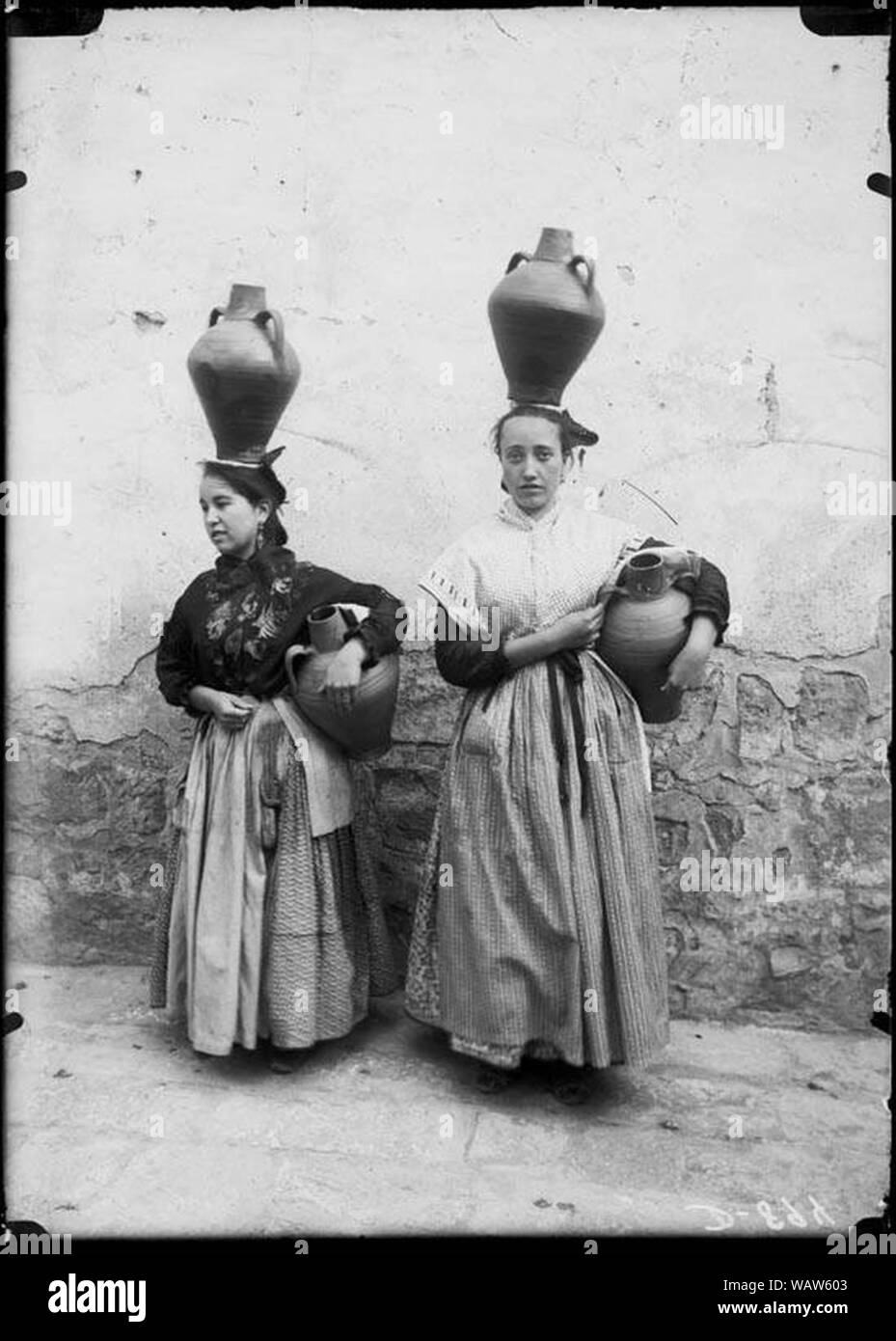 Dues noies amb indumentària tradicional i transportant càntirs. Stock Photo