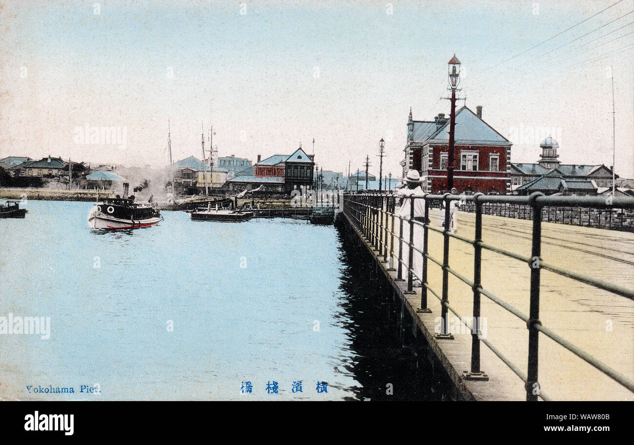 [ 1910s Japan - Yokohama Pier ] —   The pier in Yokohama Harbor, Kanagawa Prefecture.  Construction of the 19 m wide by 730 m long pier was started in 1889 (Meiji 22) and completed in 1894 (Meiji 27).  The red brick building in the back housed the Yokohama Customs Office Inspection Bureau (税関監視課庁舎) and was completed in the same year as the pier.  20th century vintage postcard. Stock Photo