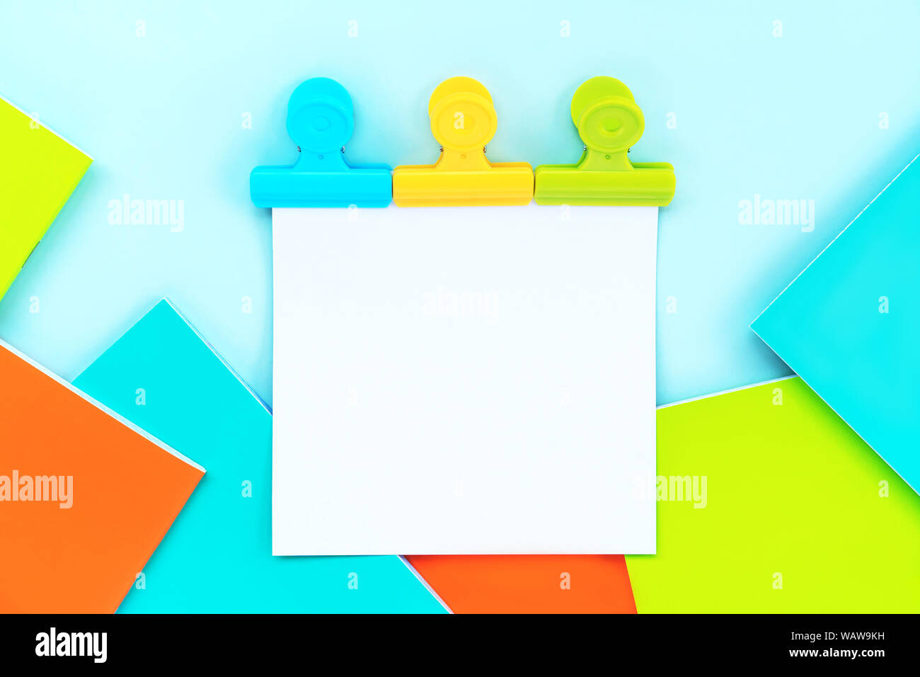 A white sheet for writing attached by three multi-colored stationery clips  Stock Photo