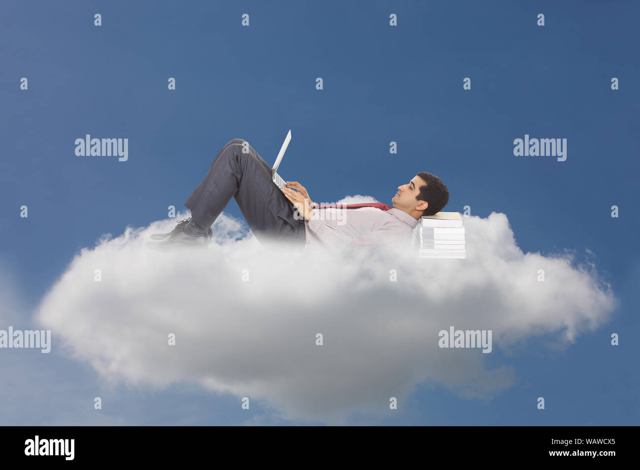 Businessman lying on clouds and using laptop concept cloud computing Stock Photo