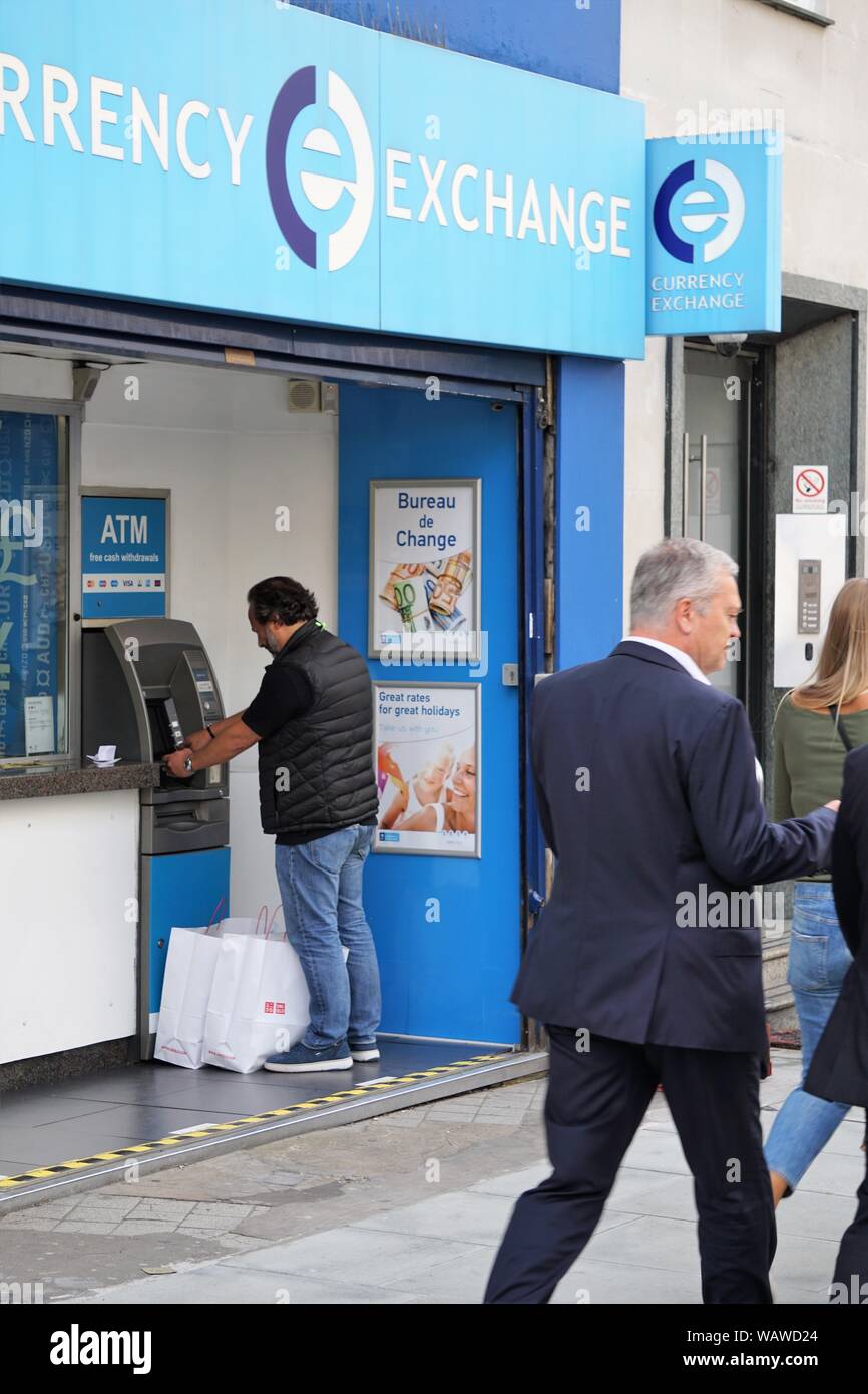 Man withdrawing money from an ATM machine at the branch of Currency Exchange in Oxford Street, London, UK Stock Photo
