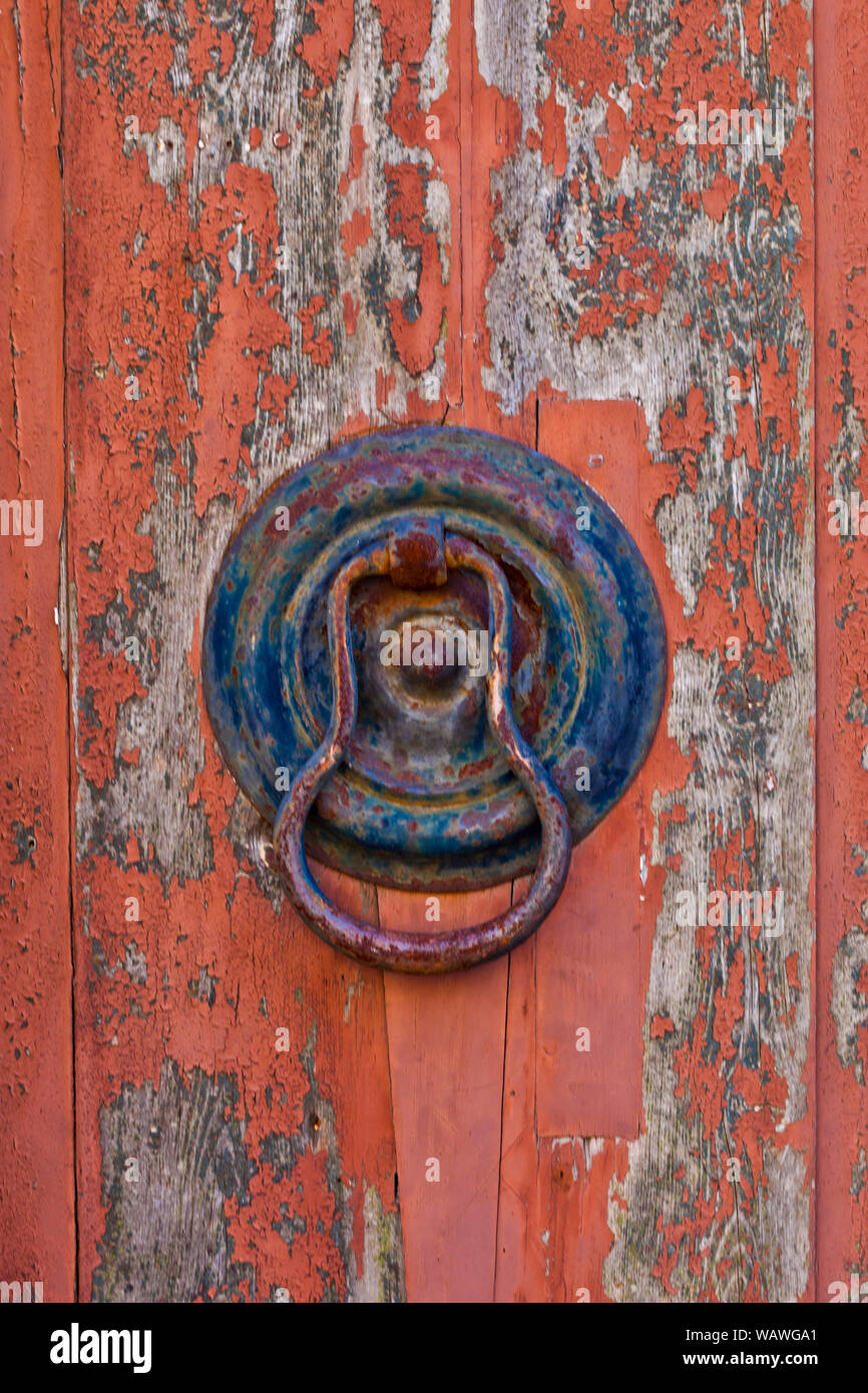 Ancient italian door knocker on old wooden red background Stock Photo