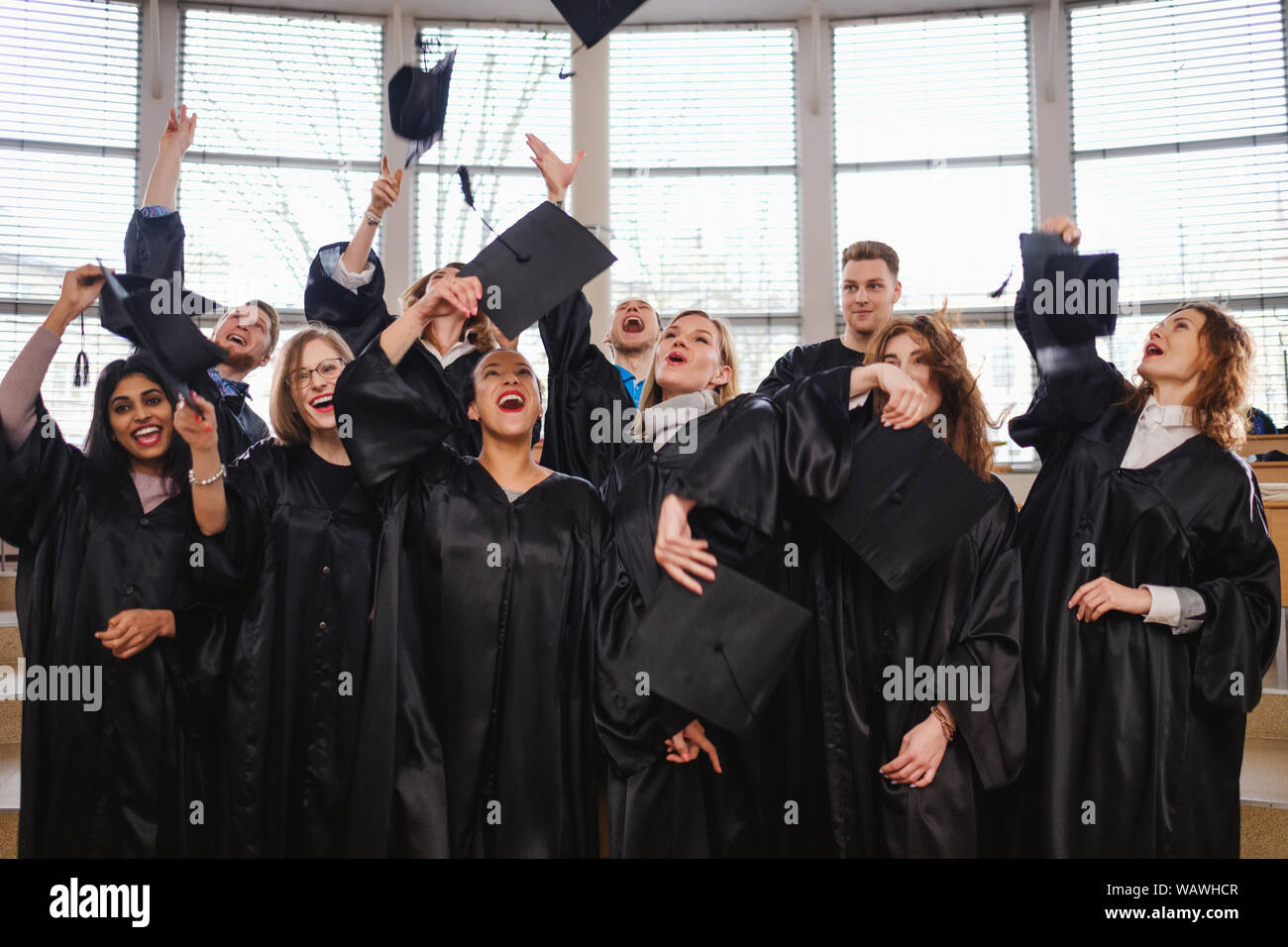 Multi ethnic group of graduated students throwing hats Stock Photo - Alamy