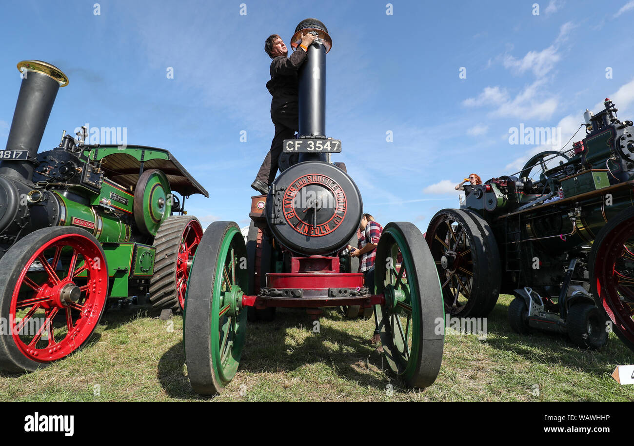 A person polishes the chimney on their Clayton & Shuttleworth General Purpose Engine during day one of the 2019 Great Dorset Steam Fair. The fair is a gathering of hundreds of period steam traction engines and heavy mechanical equipment from all eras come to showcase Great Britain's rich industrial, agricultural and leisure history, at the annual show taking place over the August Bank Holiday weekend from Thursday 22nd to Monday 26th August. Stock Photo