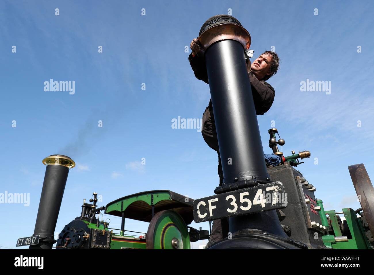 A person polishes the chimney on their Clayton & Shuttleworth General Purpose Engine during day one of the 2019 Great Dorset Steam Fair. The fair is a gathering of hundreds of period steam traction engines and heavy mechanical equipment from all eras come to showcase Great Britain's rich industrial, agricultural and leisure history, at the annual show taking place over the August Bank Holiday weekend from Thursday 22nd to Monday 26th August. Stock Photo