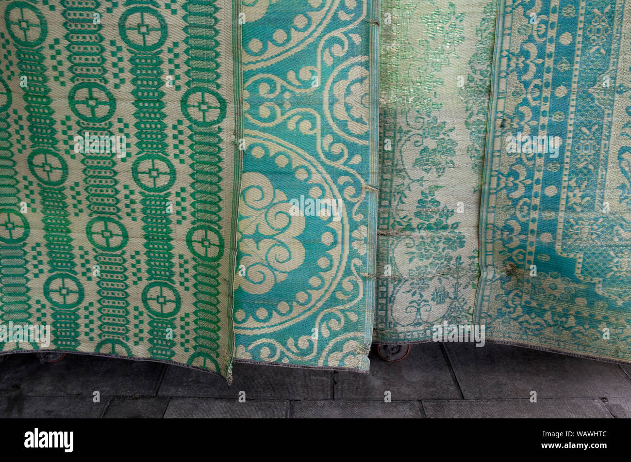 A Close Up A Selection Of Green Patterned Rugs Hung Up For Display On A