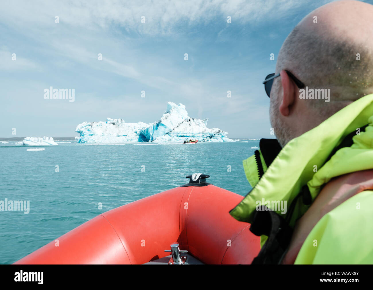 Tourist in safety flotation suit views an iceberg from a zodiac rib boat on the glacier lagoon at Jokulsarlon, iceland Stock Photo