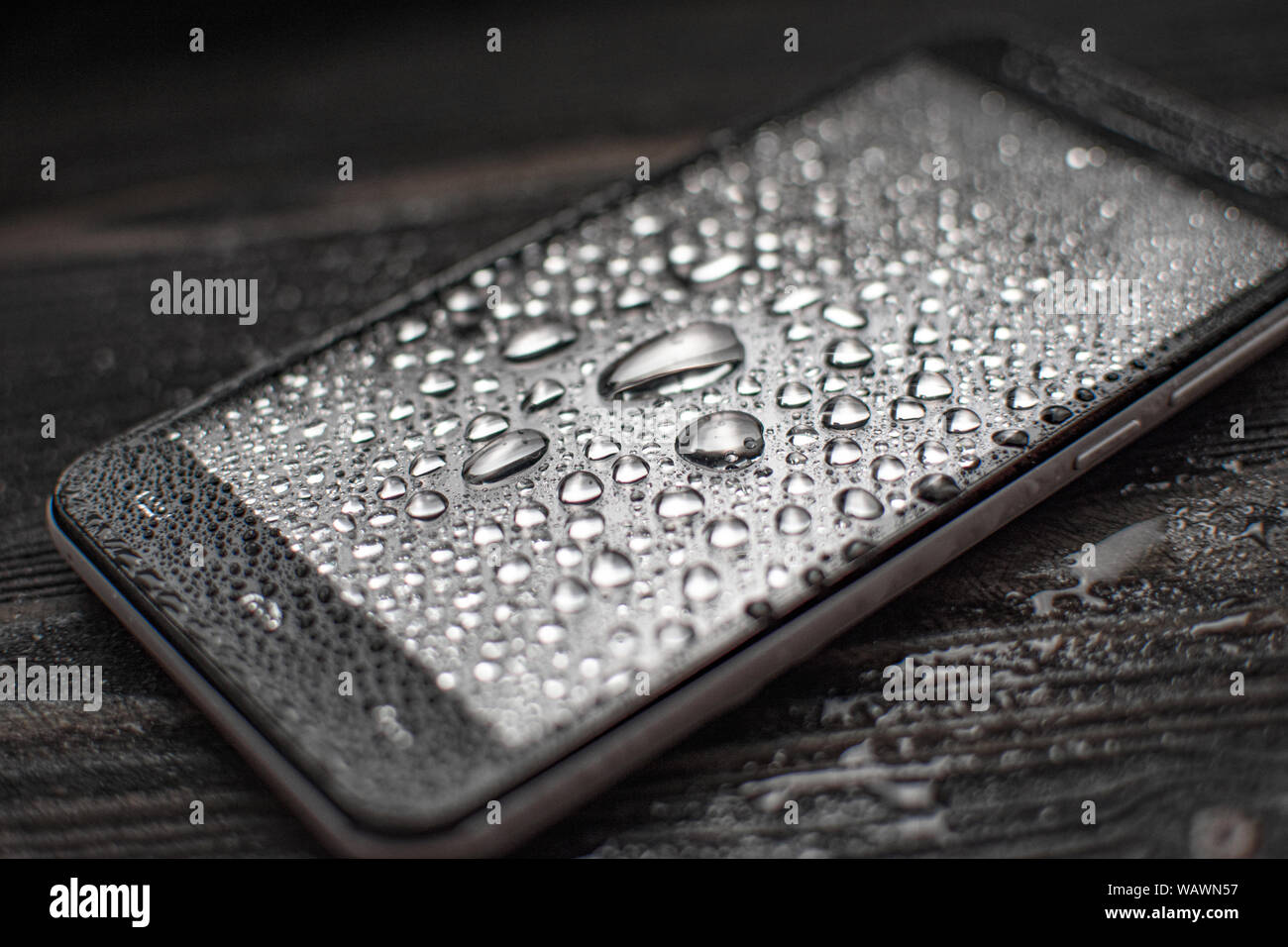 Liquid Water Drops On Glass Of Smartphone On Wooden Desk Surface