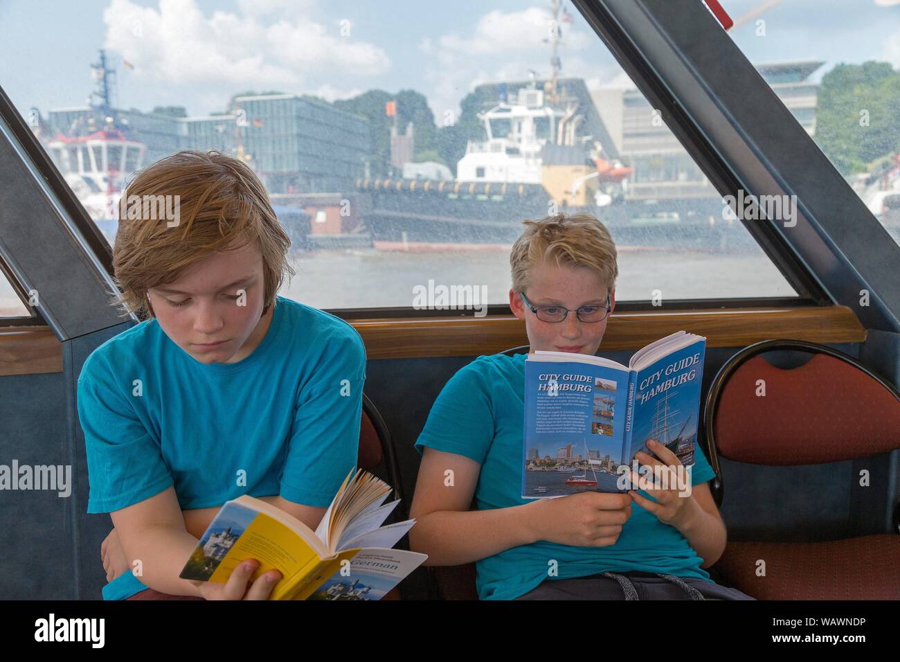 Young people on a language trip read an English travel guide on the Elbe ferry, Hamburg, Germany Stock Photo