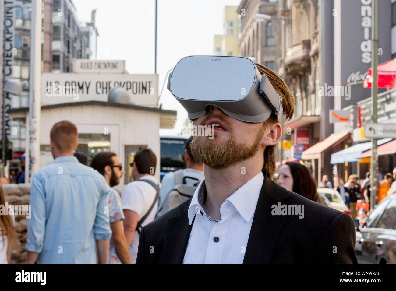 Berlin, Germany. 22nd Aug, 2019. Jonas Rothe, founder and managing director of TimeRide, stands at Checkpoint Charlie during a press demonstration of a virtual journey through time in divided Berlin with virtual reality glasses. With virtual reality glasses, visitors to TimeRide near Checkpoint Charlies can visit the divided Berlin of the 1980s. Credit: Christoph Soeder/dpa/Alamy Live News Stock Photo