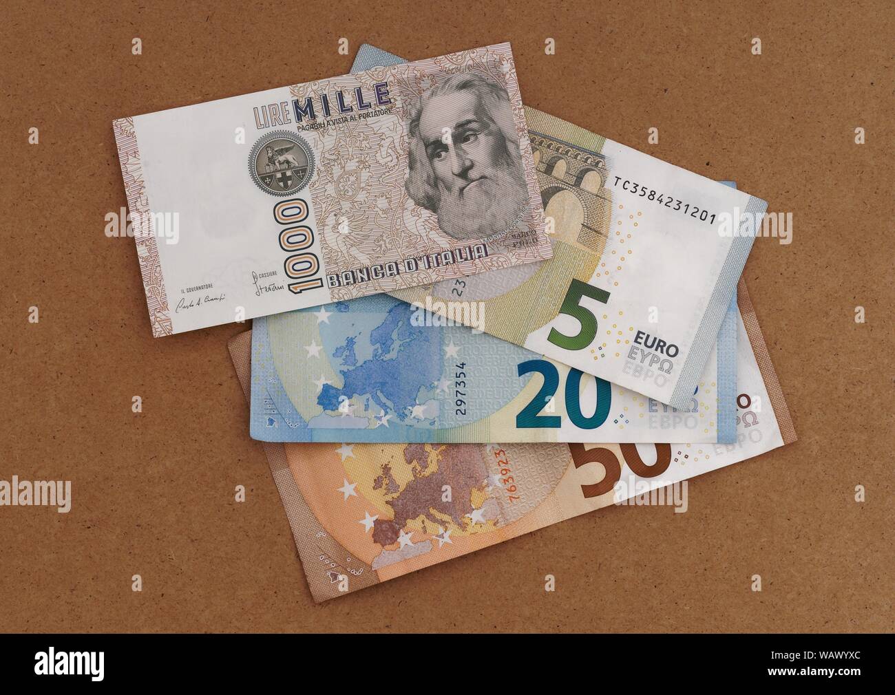 MASSA CARRARA, ITALY - AUGUST 14, 2019: Italian vintage and obsolete Lire note overlays and part obscures new Euro currency. Stock Photo