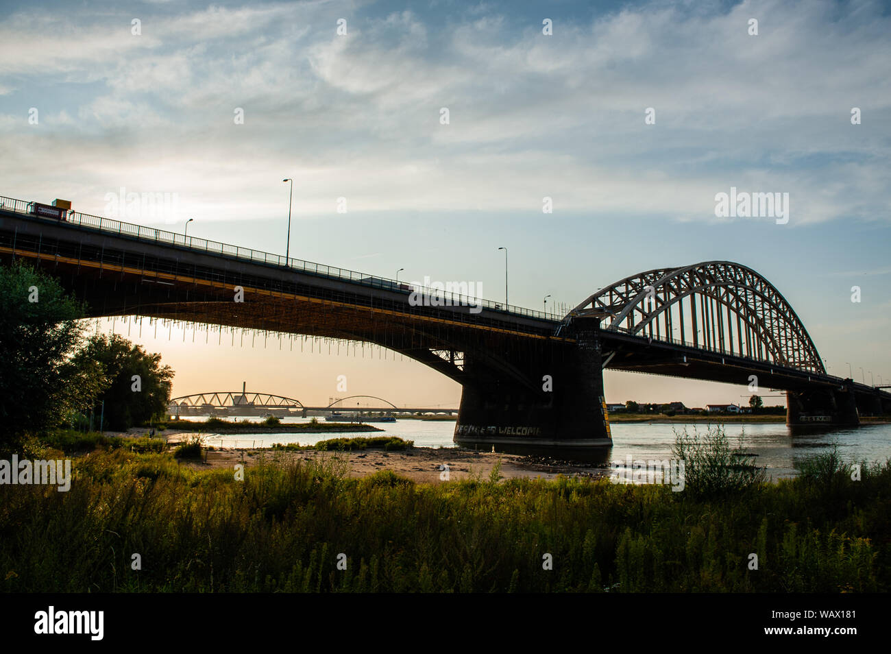 Nijmegen, Netherlands. 21st Aug, 2019. View of the Waalbrug bridge during sunset.The Ooijpolder is a beautiful area for walking and recreation close to the Waalbrug Bridge and surrounded by the Waal River. The area is located east of the city of Nijmegen in the province of Gelderland. Credit: SOPA Images Limited/Alamy Live News Stock Photo