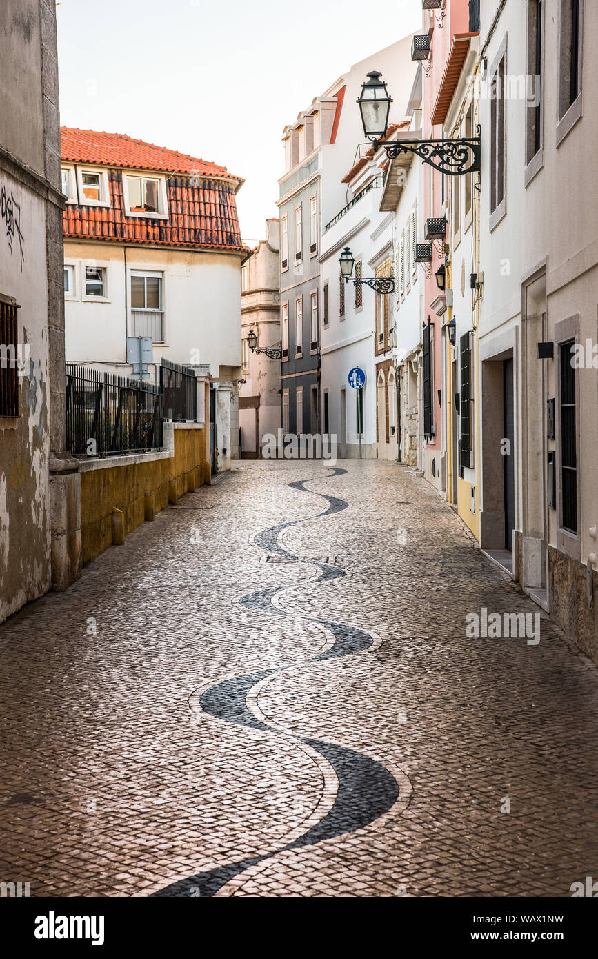 Winding narrow cobblestone alley in Portuguese pavement calçada style ...