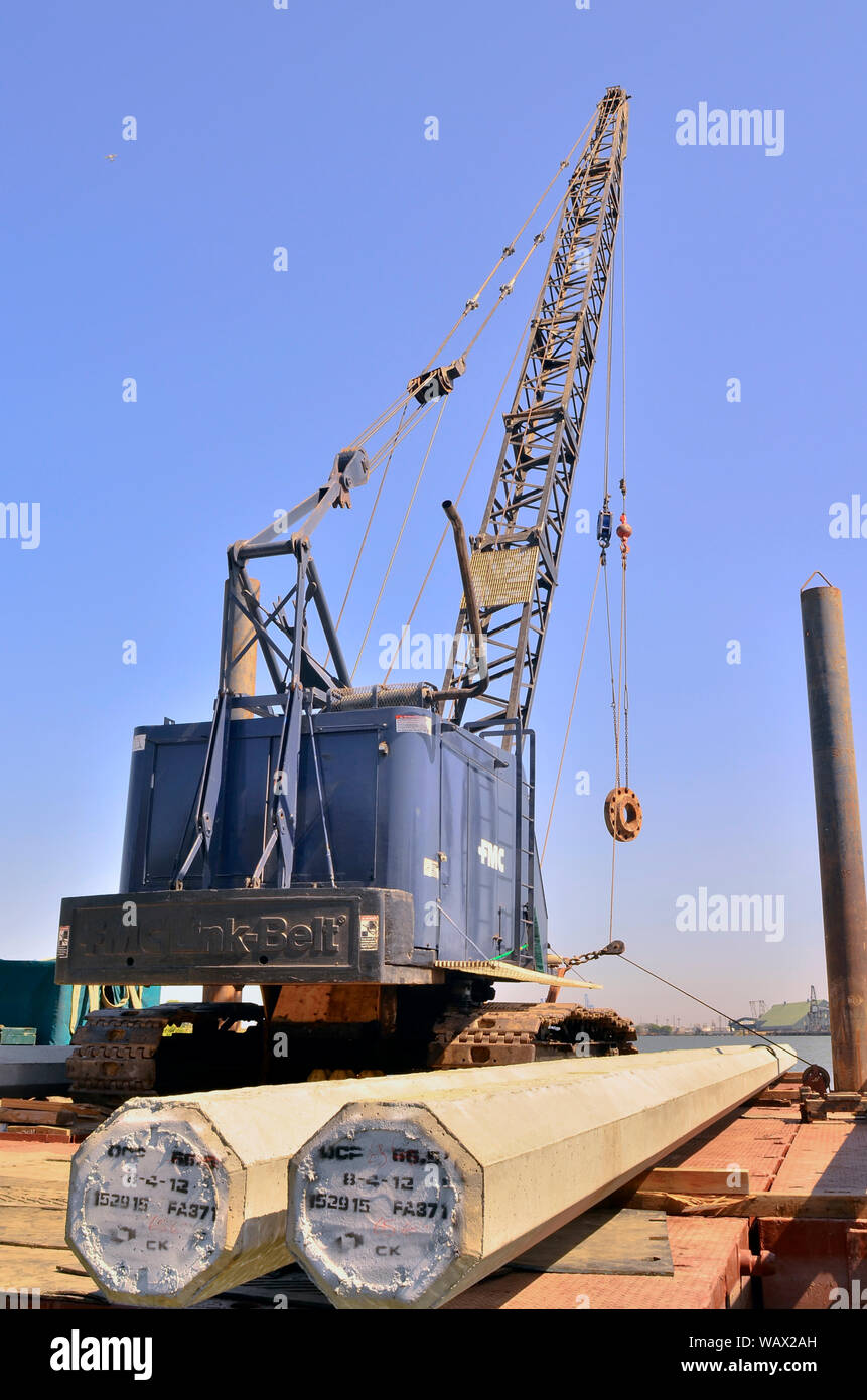 A barge with two concrete piles and a FMC Link-Belt crane positioned at the boat launch ramp near the Pittsburg marina, Pittsburg, California Stock Photo