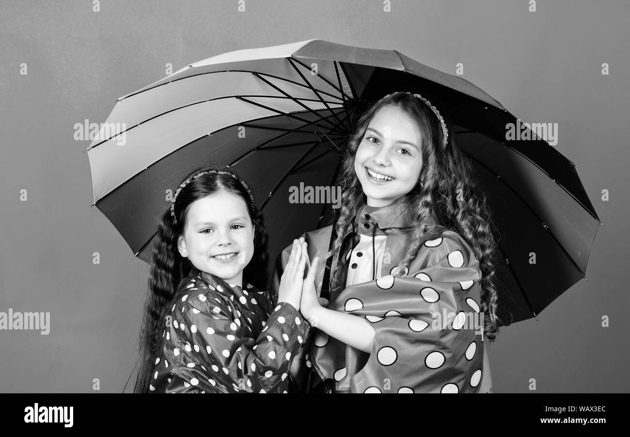 rain protection. Rainbow. autumn fashion. happy little girls with colorful umbrella. cheerful hipster children, sisterhood. family bonds. Little girls in raincoat. Any weather is good. Stock Photo