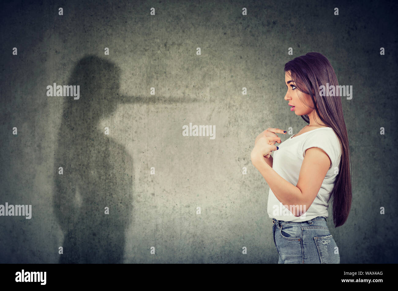 Side view of a woman pointing at herself looking at a shadow with long nose of a liar. Stock Photo