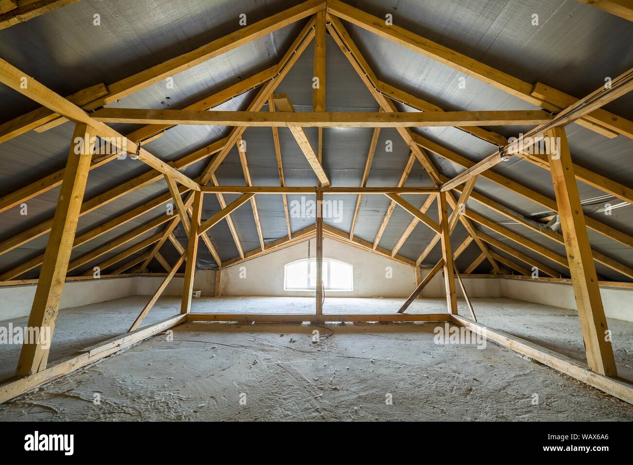 Attic of a building with wooden beams of a roof structure and a small ...