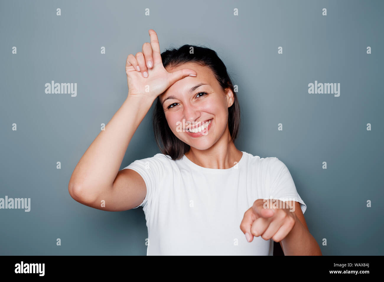 Funny woman making fun of someone with loser hand gesturing Stock Photo