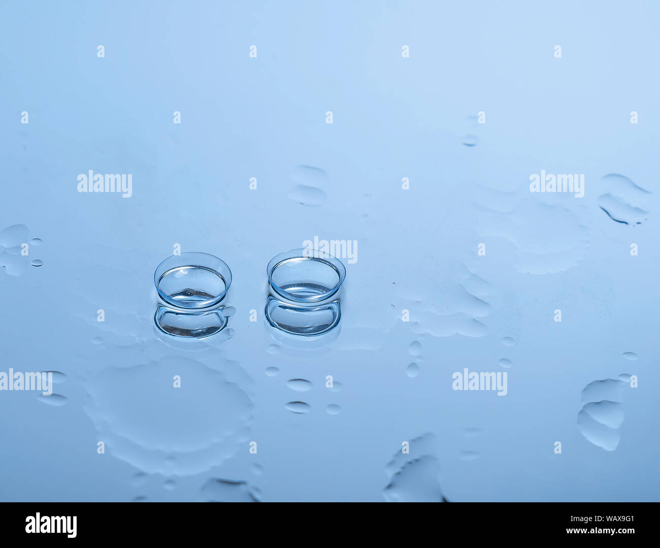 Contact lenses for the eyes on the glass among the drops of water in