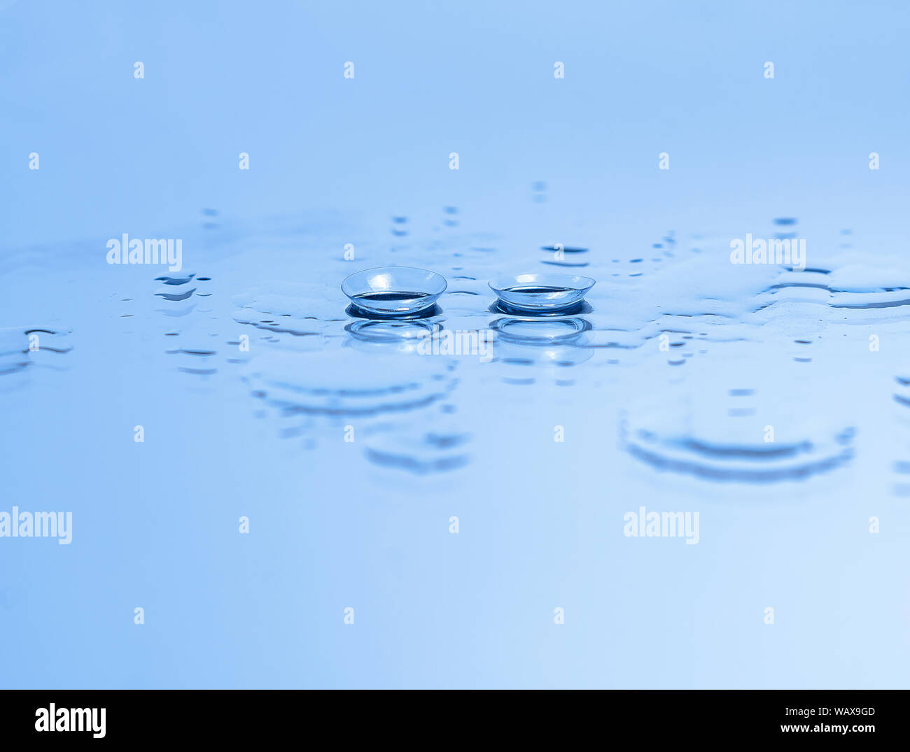 Contact lenses for the eyes on the glass among the drops of water in