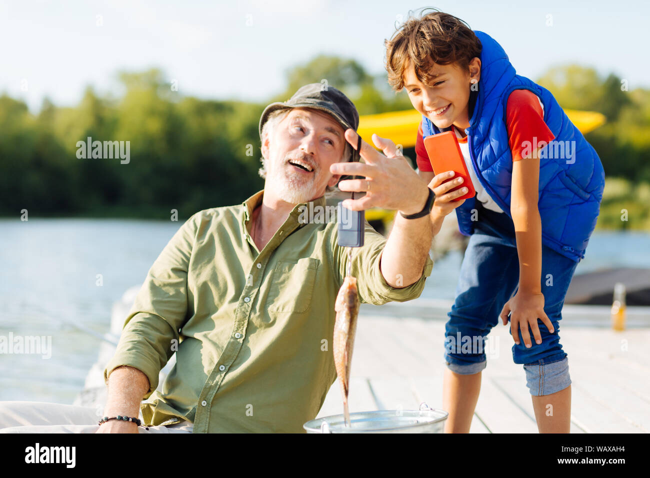 Boy making photo of big fish while fishing with grandfather Stock Photo ...