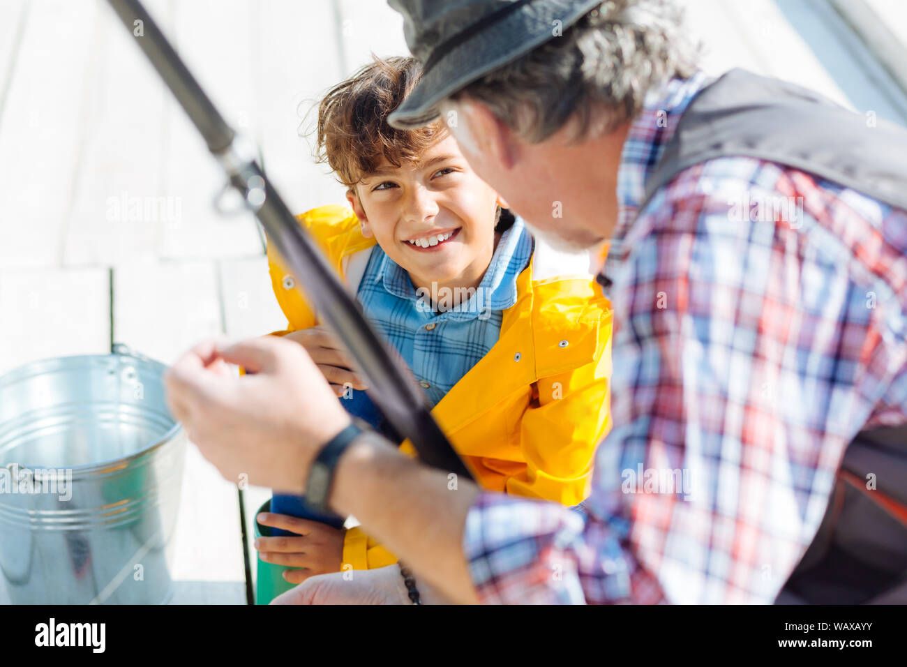 Handsome smiling dark-eyed boy fishing with grandfather Stock Photo