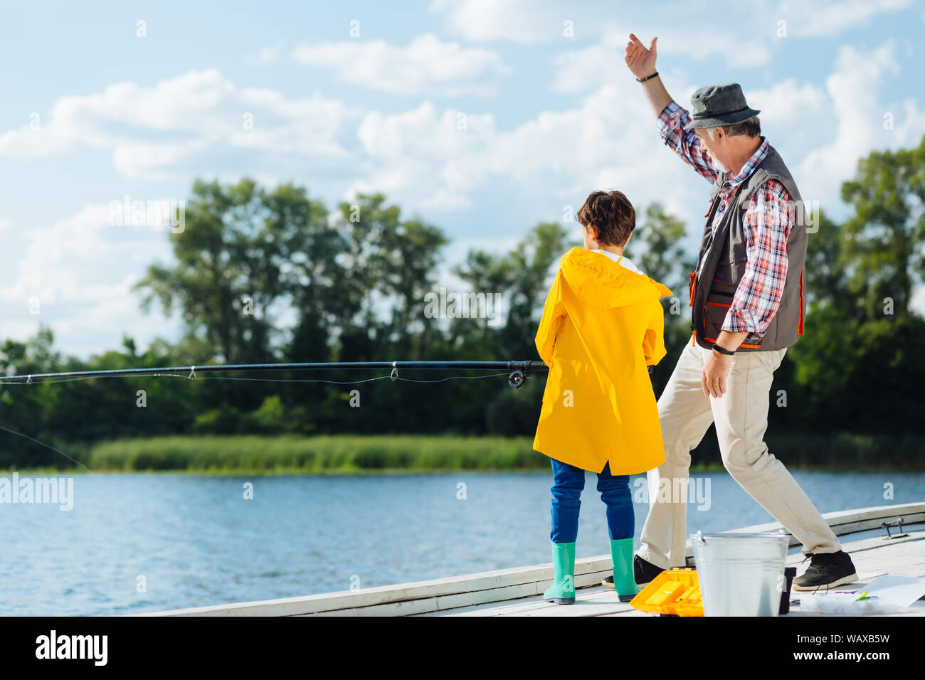 Boy wearing yellow raincoat holding fishing tackle Stock Photo Alamy