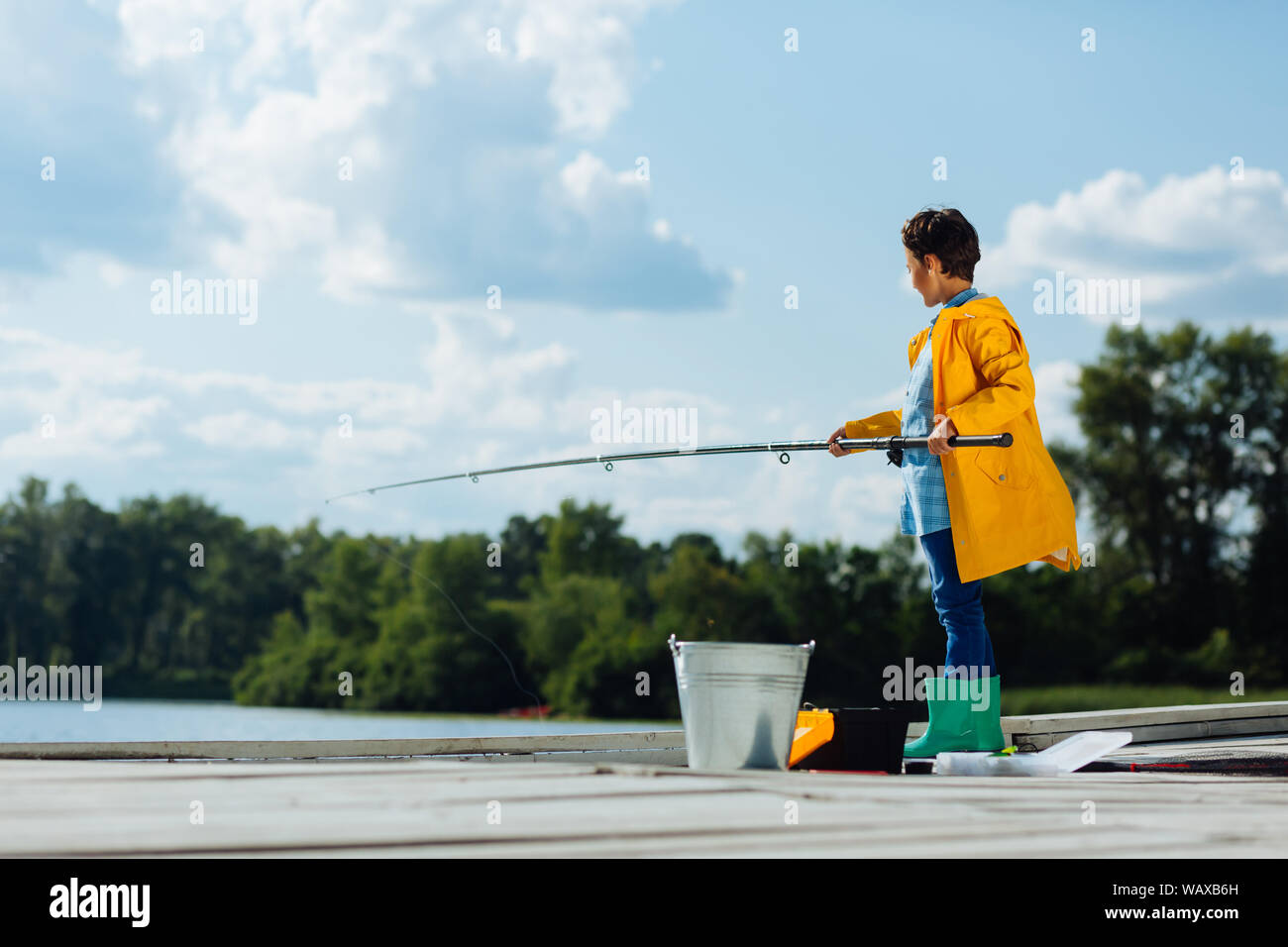 Boy wearing bright green rain boots standing and fishing Stock Photo