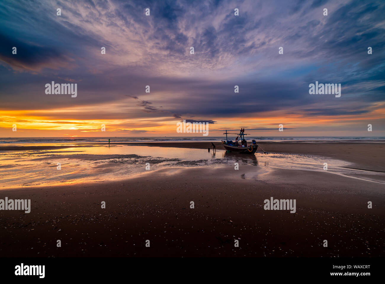 Beautiful sunrise over an old wooden fishing boat on a pebble beach ...