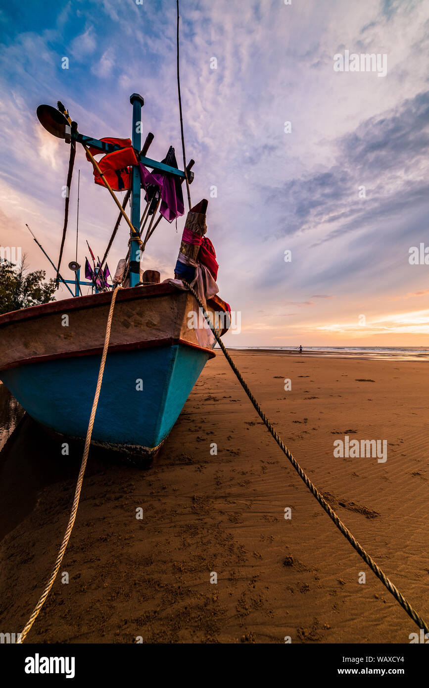 Beautiful sunrise over an old wooden fishing boat on a pebble beach ...