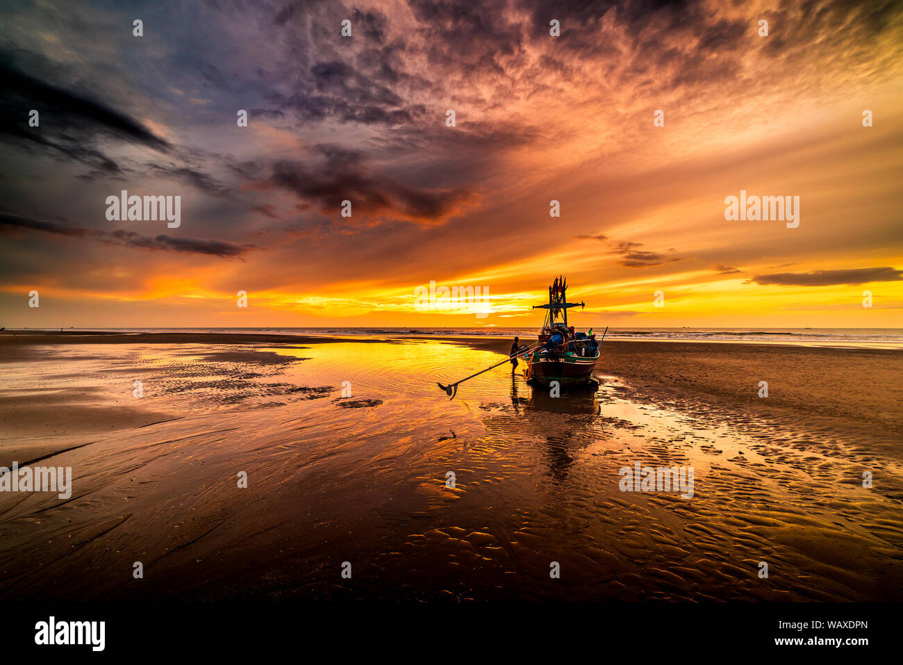 Beautiful sunrise over an old wooden fishing boat on a pebble beach ...