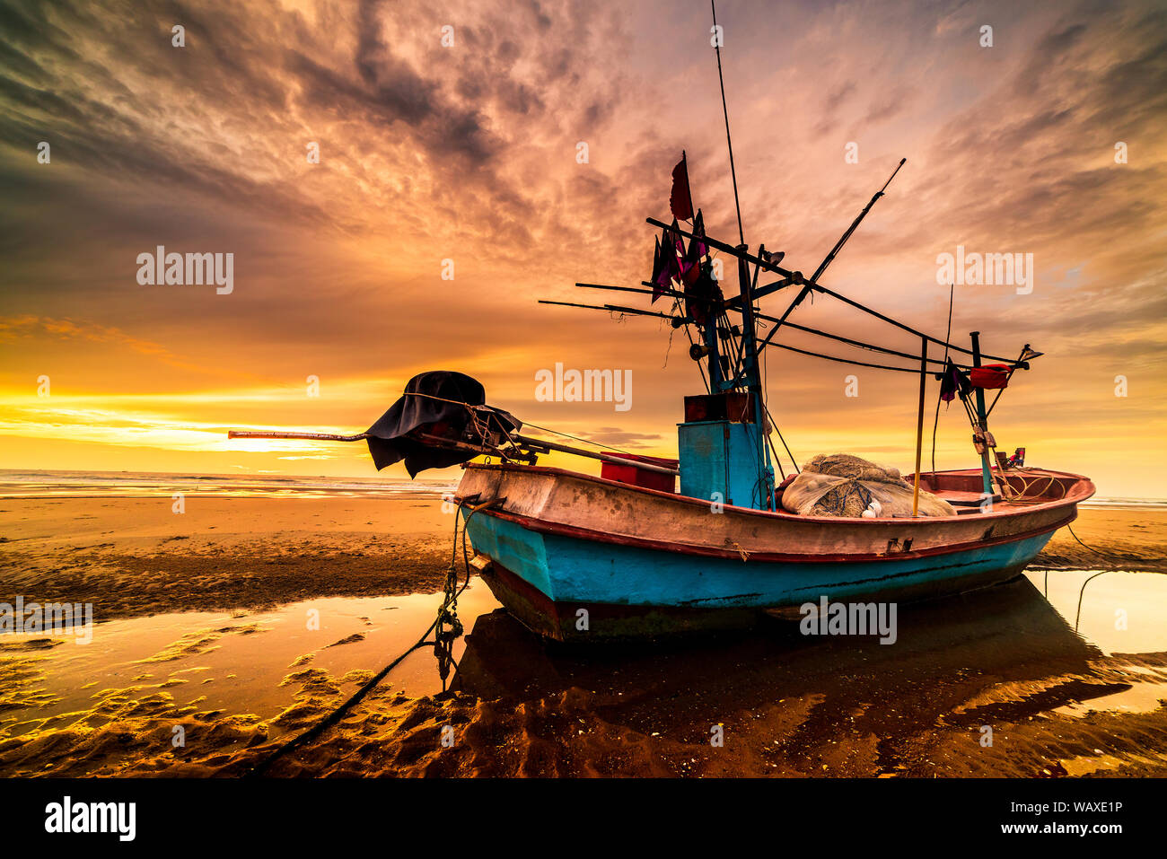 Beautiful sunrise over an old wooden fishing boat on a pebble beach ...