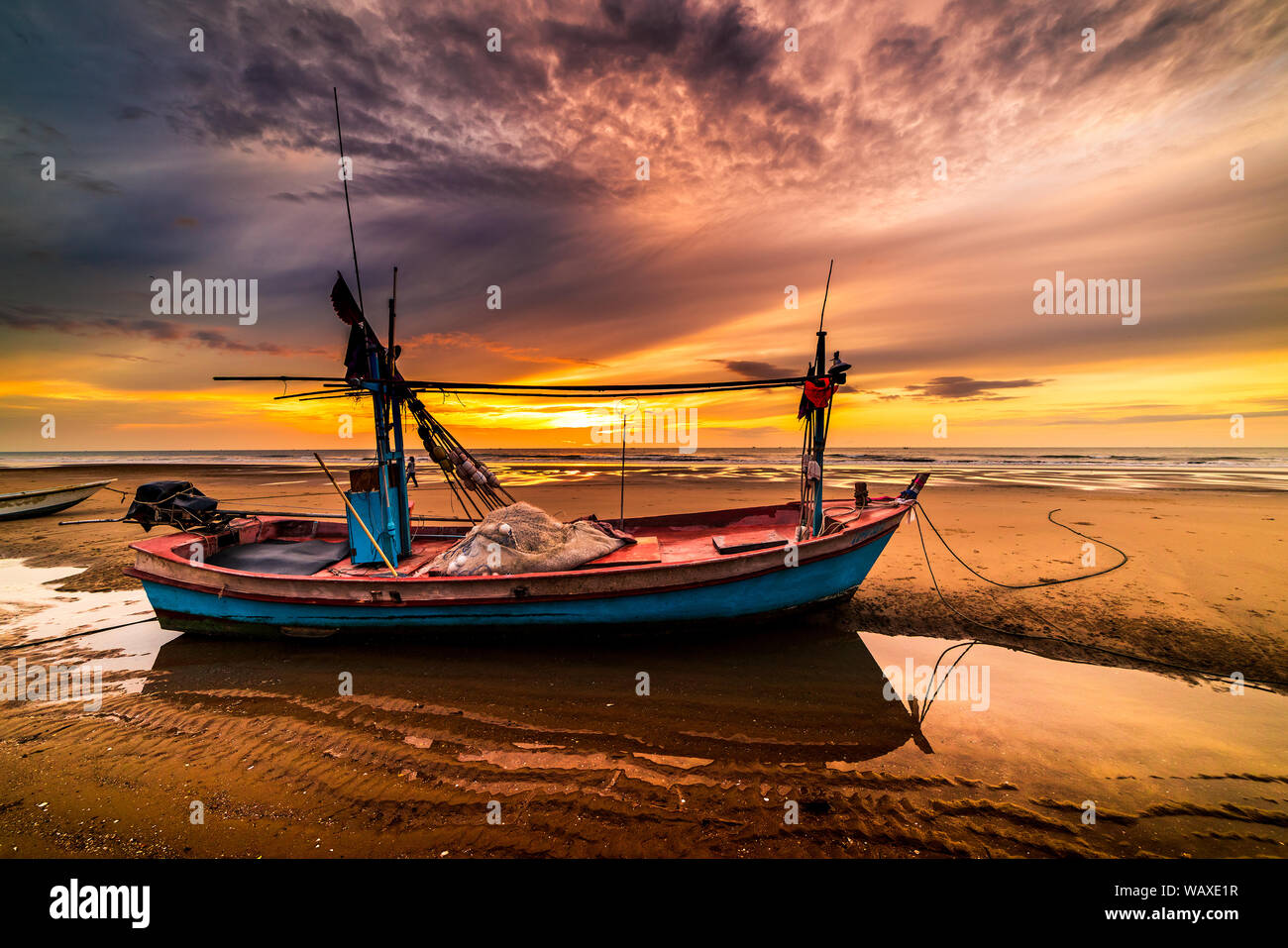 Beautiful sunrise over an old wooden fishing boat on a pebble beach ...