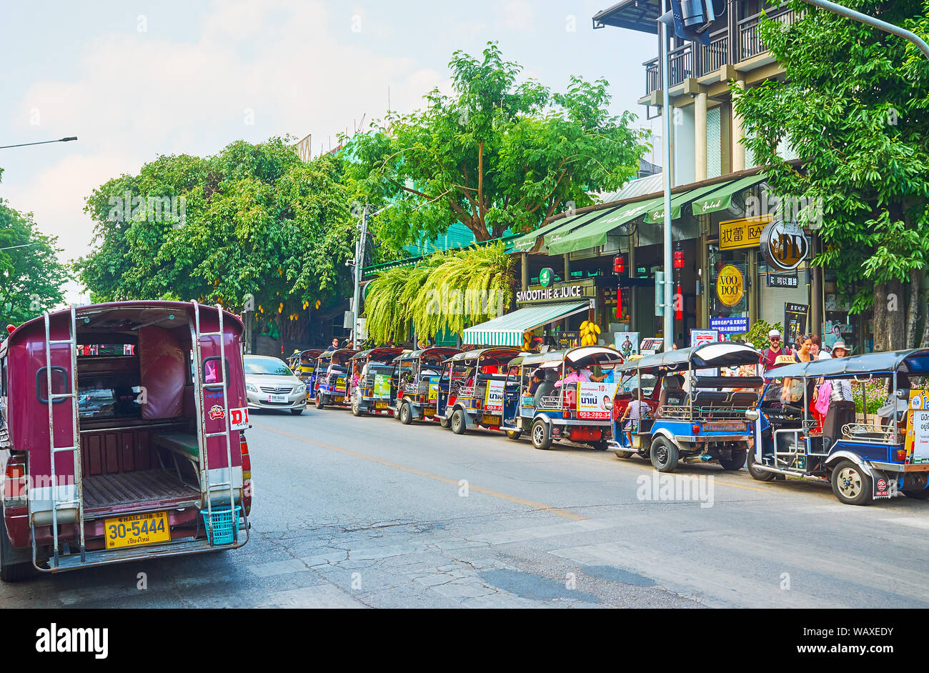 CHIANG MAI, THAILAND - MAY 2, 2019: The tourist street is lined with parked tuk tuks and songtaews - public red pickups (trucks), serving as shared ta Stock Photo