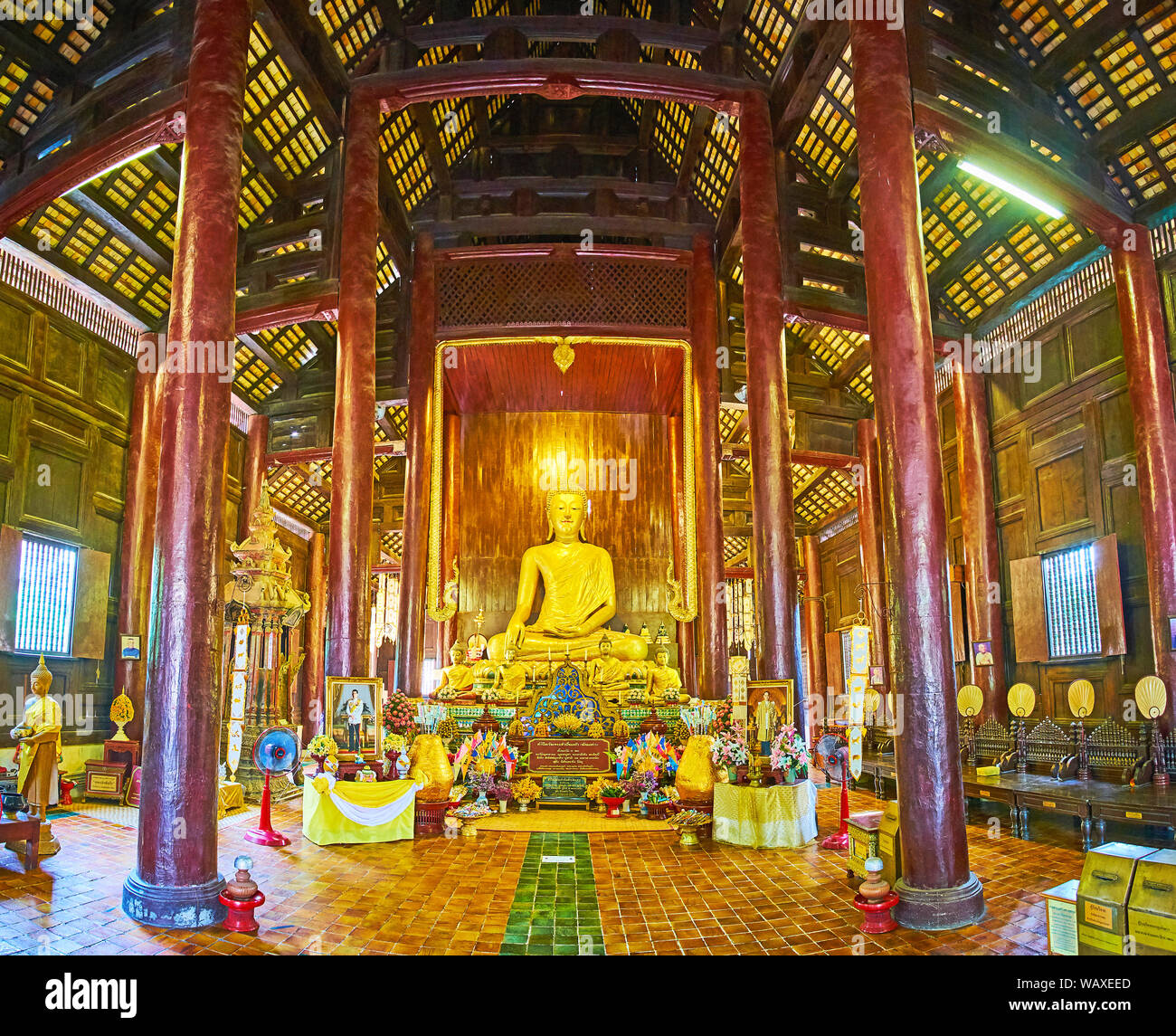 CHIANG MAI, THAILAND - MAY 2, 2019: Interior of Wat Phan Tao temple, constructed of dark teakwood with tall pillars, modest walls and ceiling, golden Stock Photo