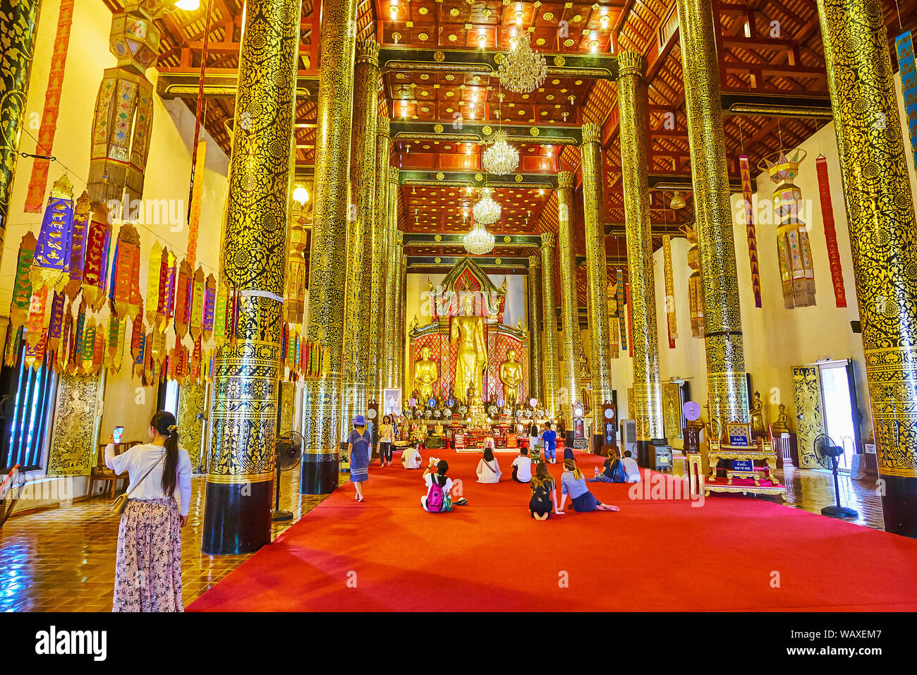 CHIANG MAI, THAILAND - MAY 2, 2019: Phra Viharn Luang prayer hall with  tall wooden columns, covered with fine patterns, vintage glass chandeliers and Stock Photo