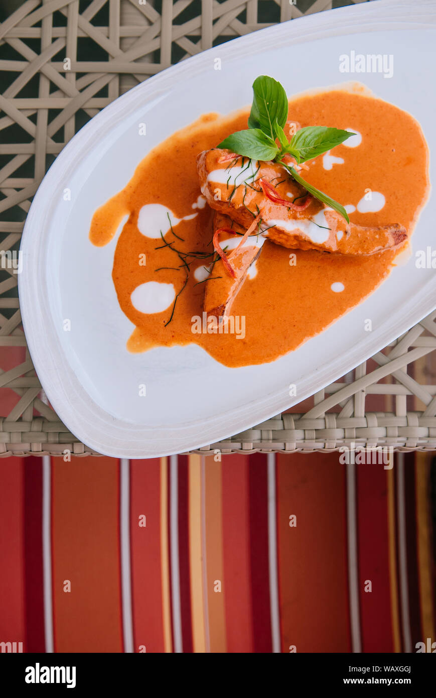 Choo Chee - grilled salmon with Thai Spicy red curry thick sauce and coconut milk, kaffir lime leaves and fresh basil. Top view Stock Photo