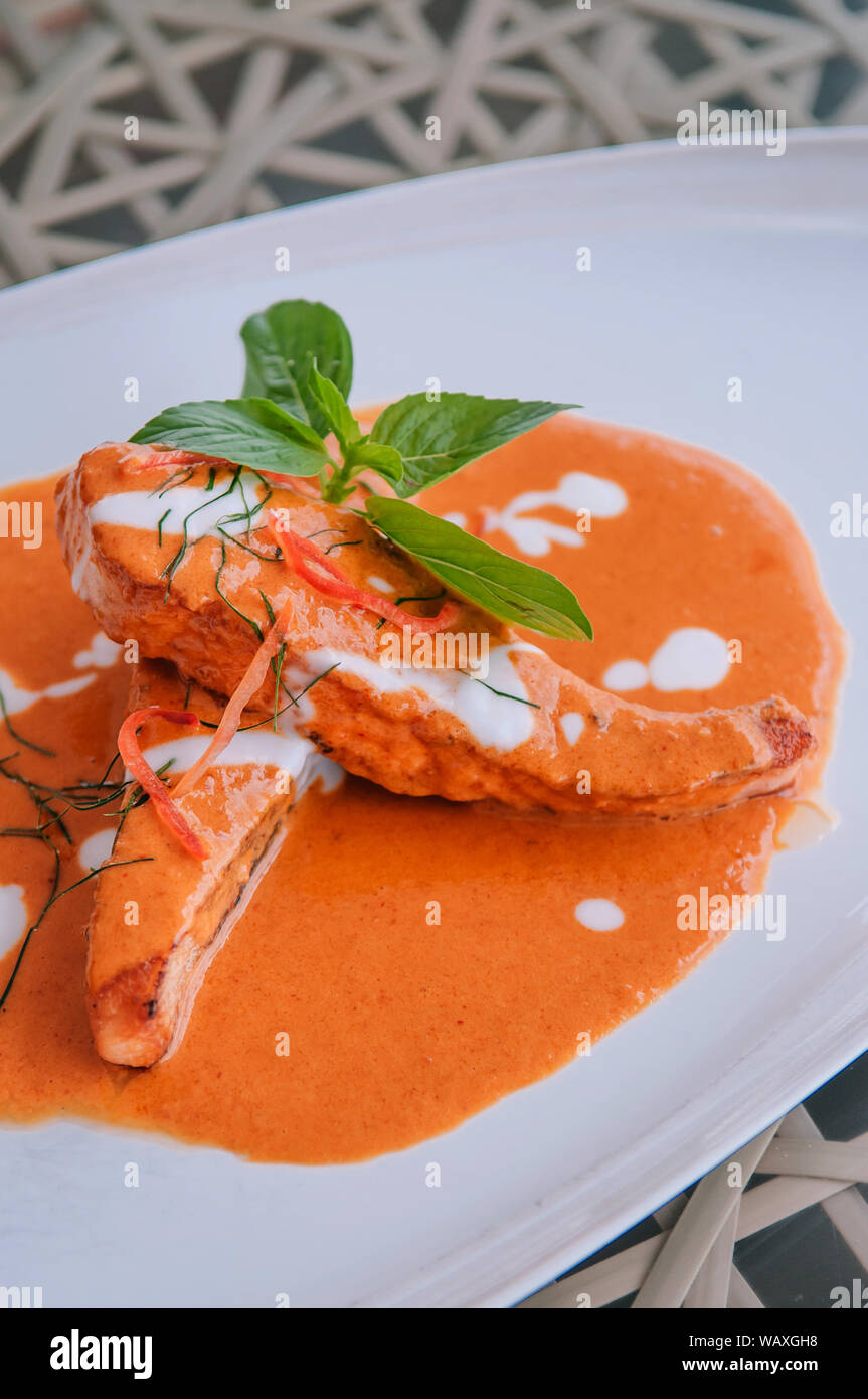 Choo Chee - grilled salmon with Thai Spicy red curry thick sauce and coconut milk, kaffir lime leaves and fresh basil. Close up shot Stock Photo