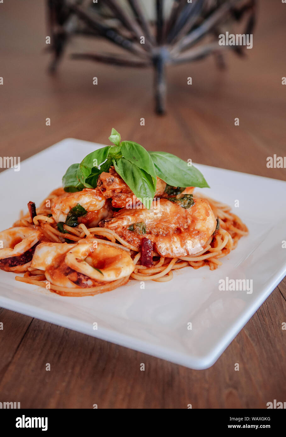 Spicy Italian Seafood Spaghetti Sugo All Arrabbiata with fresh basil on top in white plate, Lazio region style pasta. Stock Photo