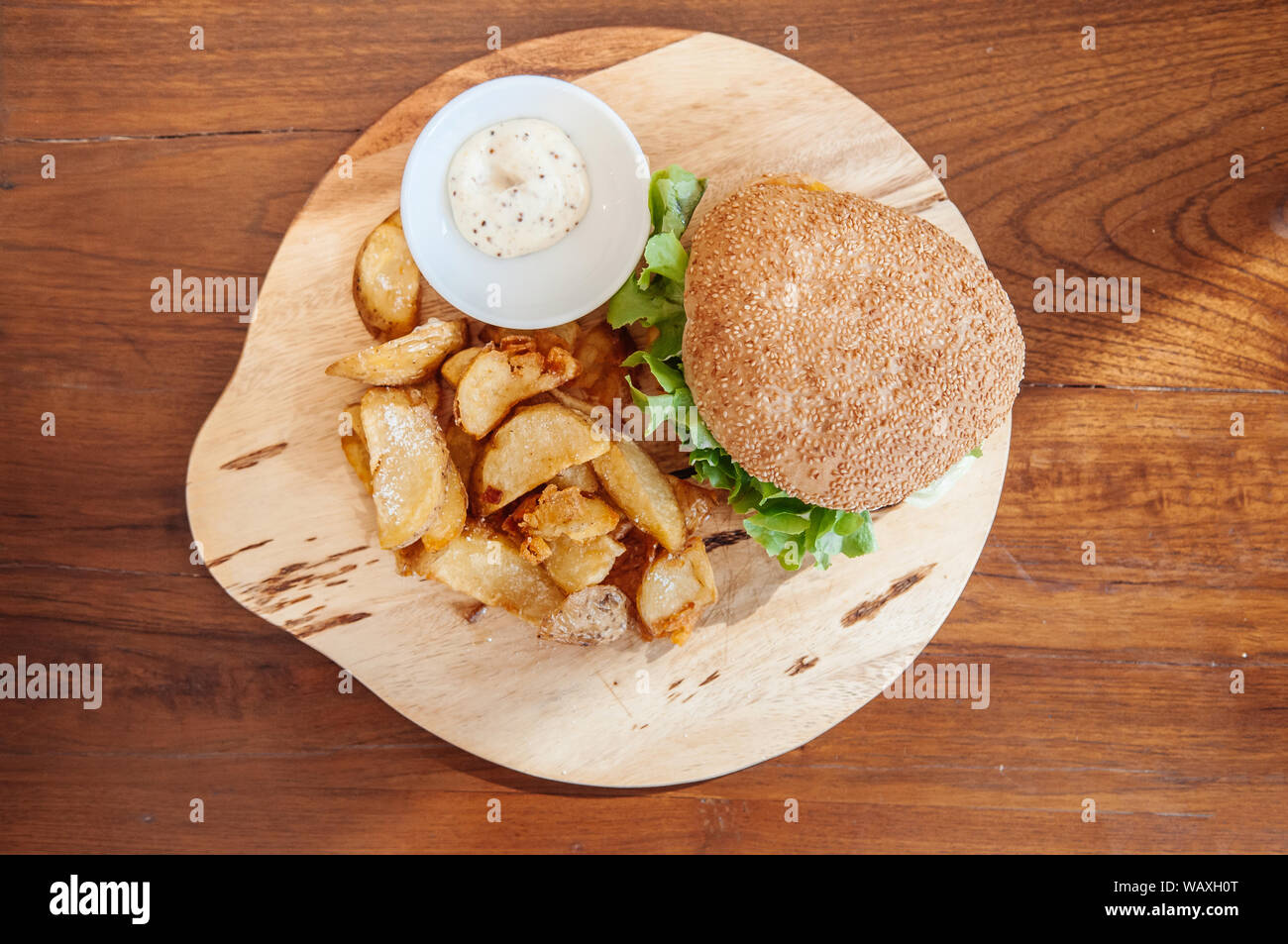 Beef cheeseburger, fried potato chunks with ranch dipping sauce on wood ...